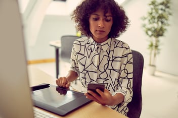 Woman at desk looking at her phone