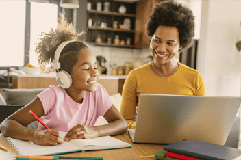 Woman working at laptop next to her daughter