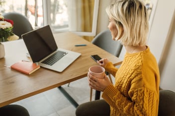 Woman with coffee in front of laptop