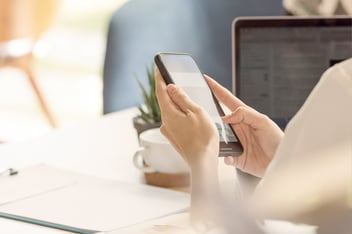 Woman on smart phone at desk