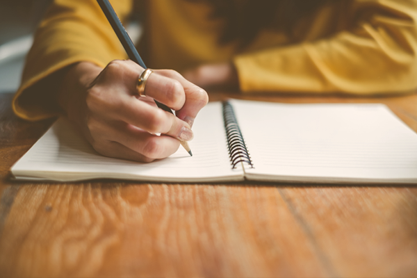 Close up of woman's hand writing in notebook